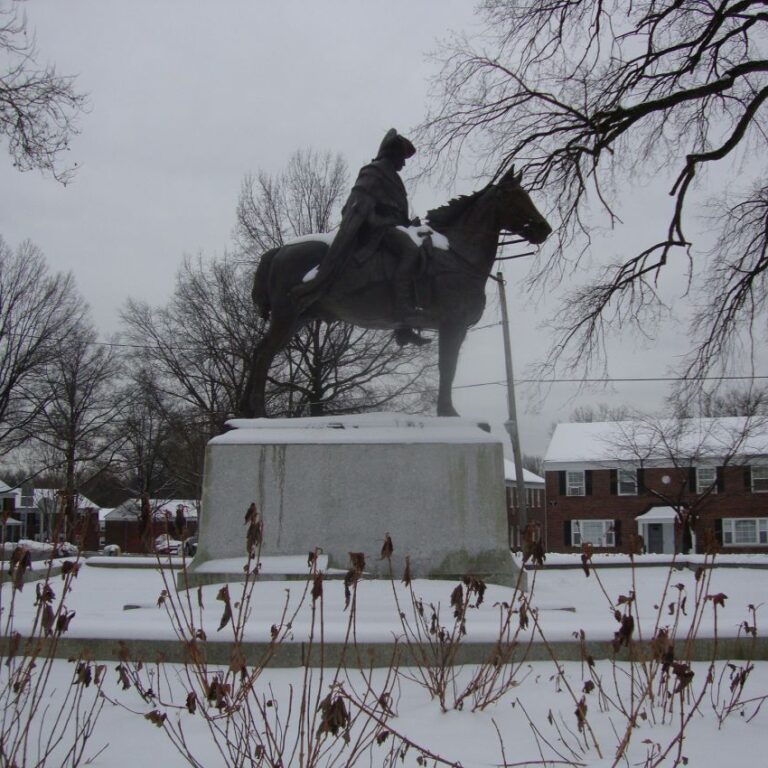 פסלו של ג'ורג וושינגטון על רקע הבית שהחרים כדי שישמש כמפקדתו