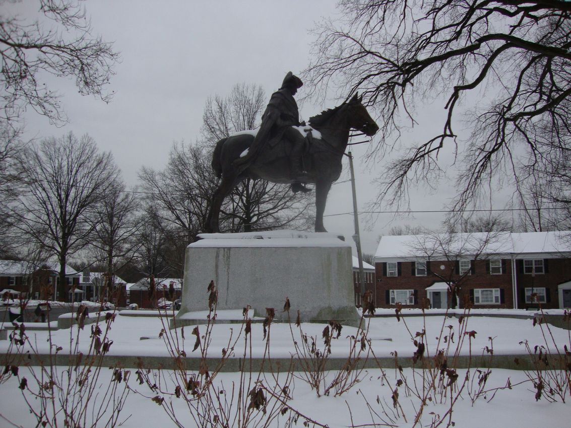 פסלו של ג'ורג וושינגטון על רקע הבית שהחרים כדי שישמש כמפקדתו