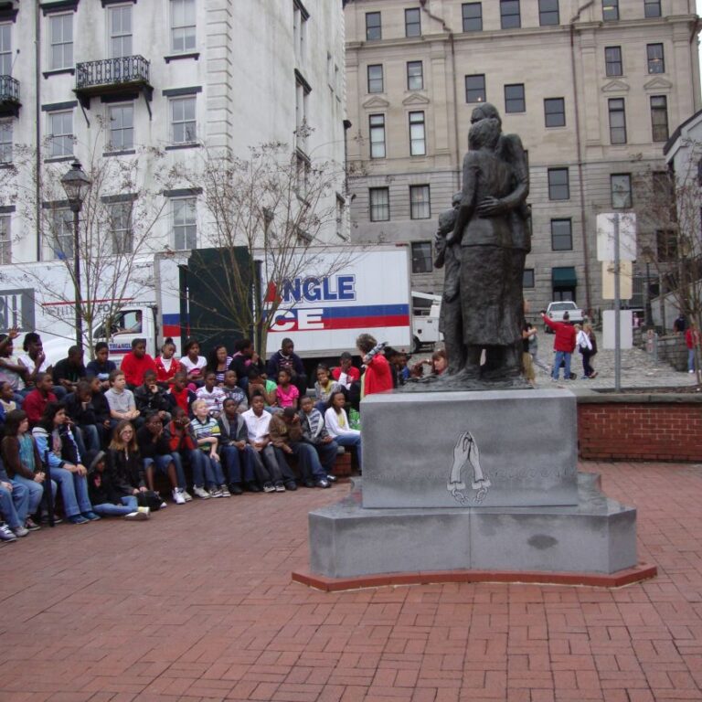 ילדים בצ'רלסטון ג'ורגיה מקבלים הסברים על תקופת העבדות מול פסל של משפחה שחורה