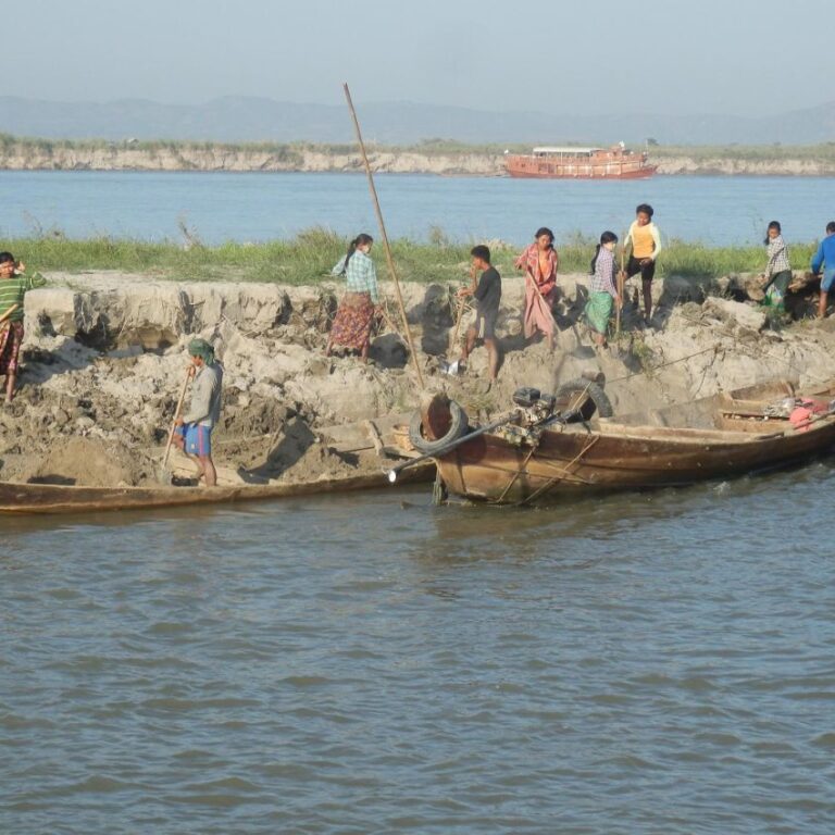 נשים מעמיסות עפר על סירות כדי להגביה את גדות הנהר
