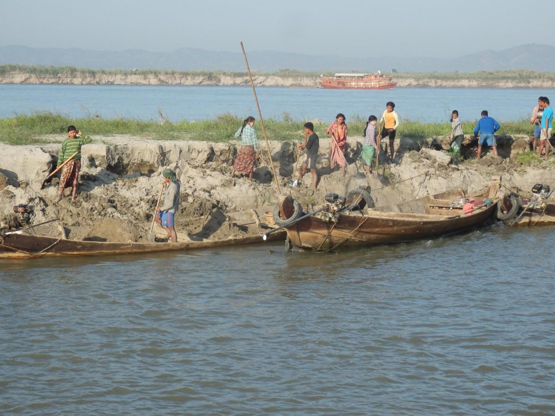 נשים מעמיסות עפר על סירות כדי להגביה את גדות הנהר