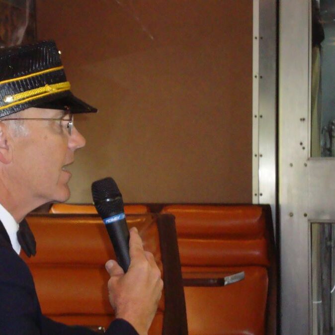 קונדוקטור מכריז על תחנות במסע הרכבת בהרי אדירונדק בצפון מדינת ניו יורק