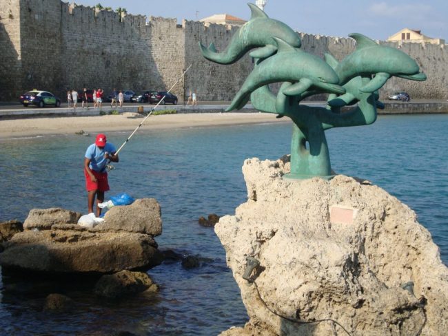 דולפינים ודייג בנמל יווני