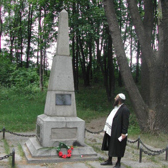 האיש מאחורי הנסיעות לאומן ליד אנדרטה לזכר עשרות אלפי היהודים שנרצחו באומן