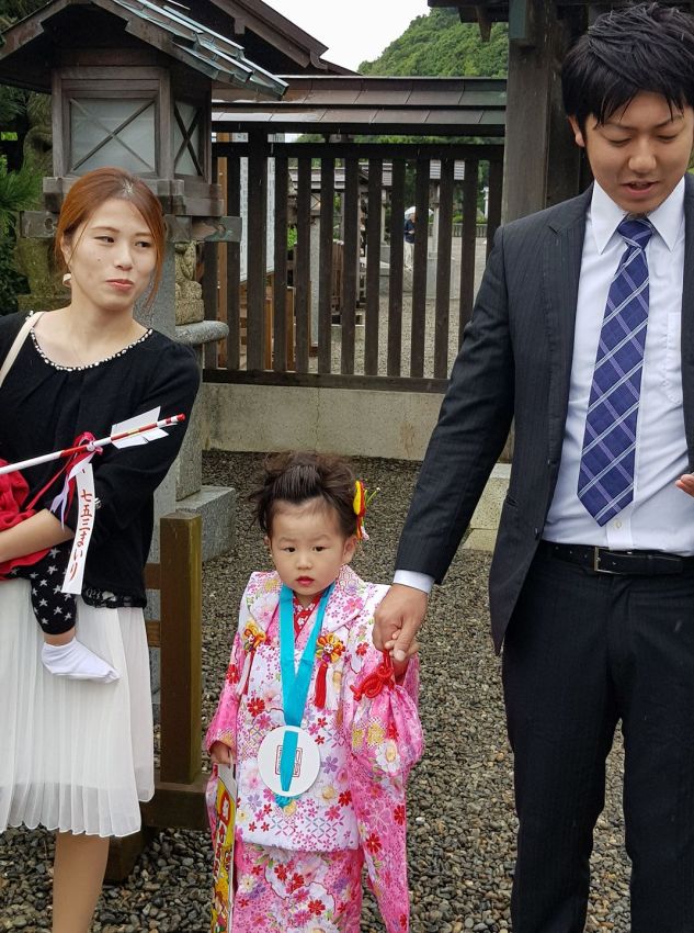 משפחה יפנית גאה מביאה את בתם לטקס במקדש שינטו