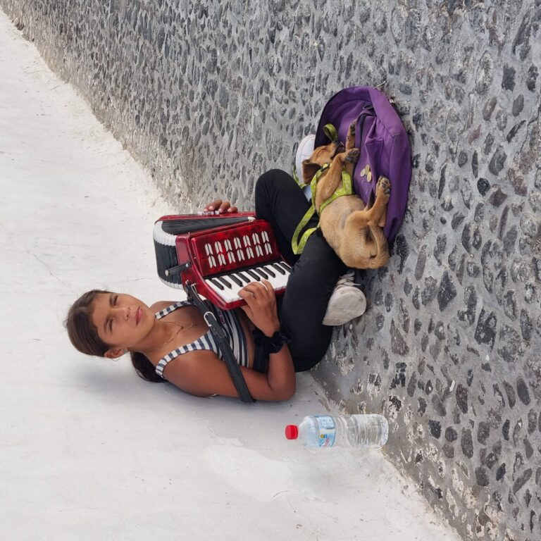 נערה באי סנטוריני מנגנת לפרנסתה את השיר מ"זורבה היווני"