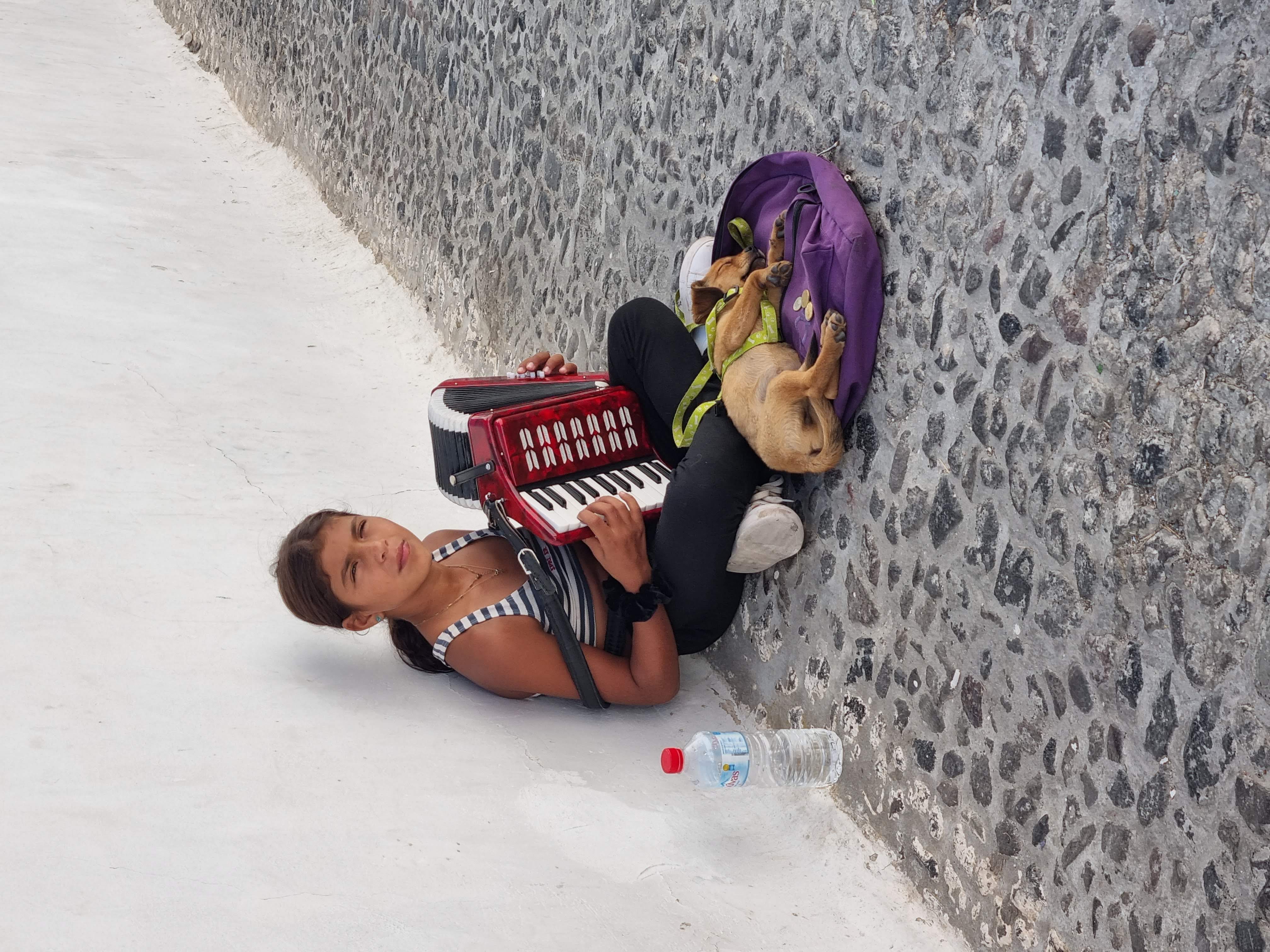 נערה באי סנטוריני מנגנת לפרנסתה את השיר מ"זורבה היווני"