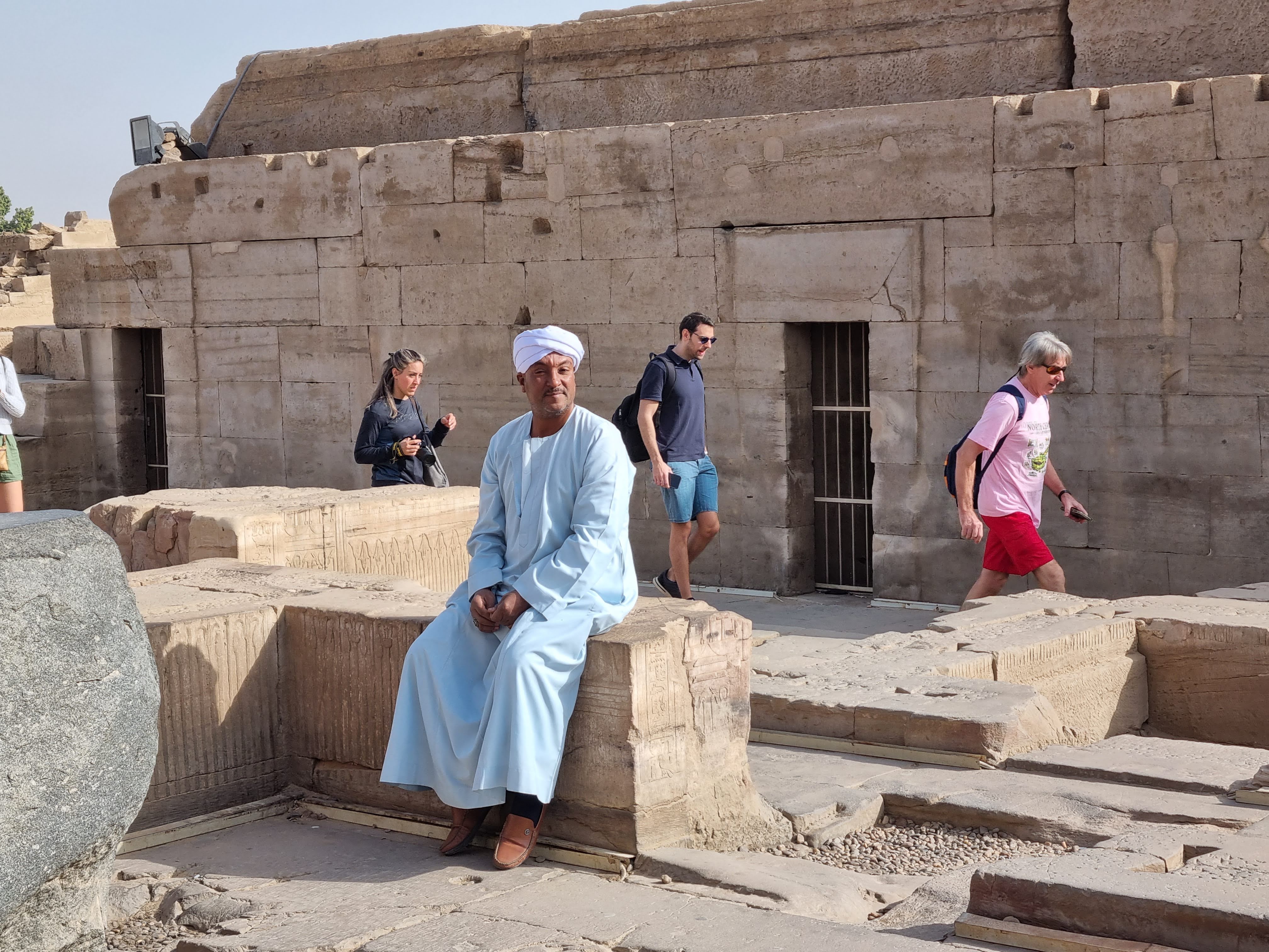 מצרי משועמם צופה בתיירים המבקרים במקדש קום אומבה בעוד הוא מסתפק בתפילה במסגד. אבל המקדשים הפאגניים הללו , מה לעשות , מביאים פרנסה לכפר הסמוך
