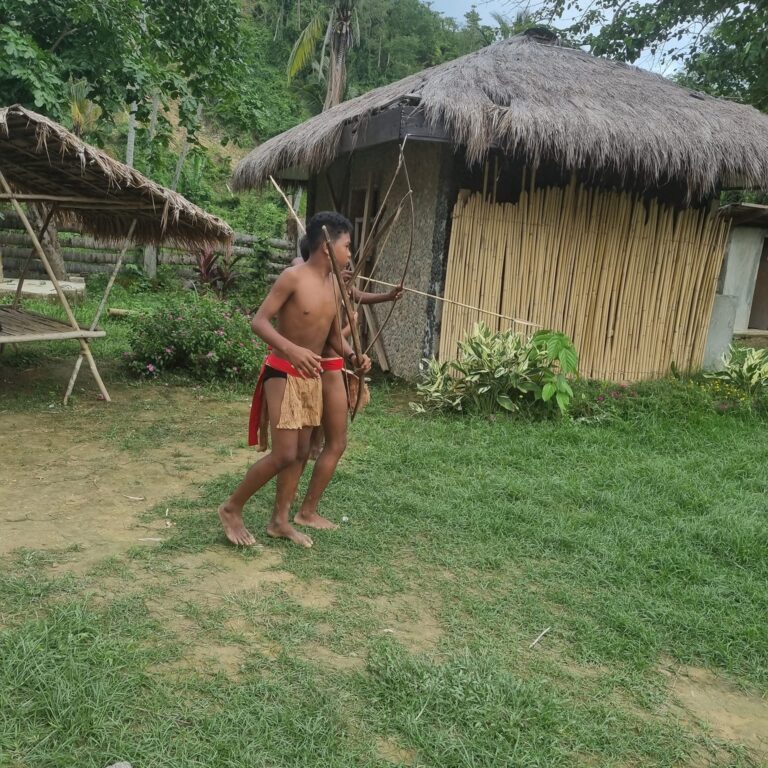 לוחמי השבט מדגימים מטווח של ירי קשתות לשם ציד חיות ביער