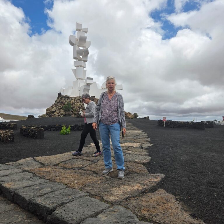 צביה על רקע האנדרטה של האמן שהמציא את האי לנסרוט לתיירות העולמית על מופעי הלבה הייחודיים שלה